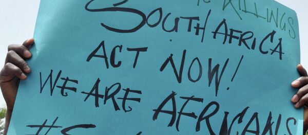 A demonstrator holds a banner in Abuja to protest against anti-immigrant violence - Sputnik Afrique