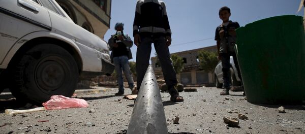 Boys stand in front of an artillery shell partially buried in the ground along a street damaged by an air strike on Monday that hit a nearby army weapons depot, in Sanaa April 21, 2015. - Sputnik Afrique