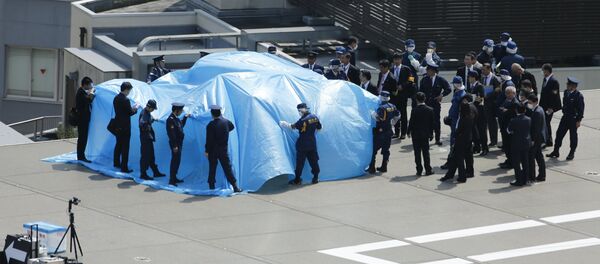 Police and security officials stand around a tarpaulin covering a drone on the roof of Prime Minister Shinzo Abe's official residence in Tokyo April 22, 2015 - Sputnik Afrique