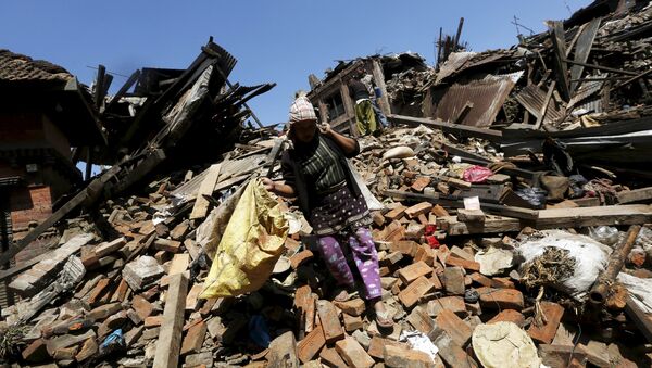 A woman carries her belongings as she walks over collapsed house after earthquake in Bhaktapur, Nepal April 27, 2015 - Sputnik Afrique