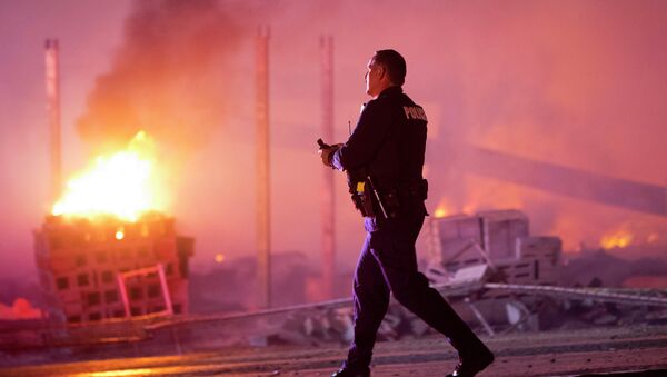 A police officer walks by a blaze in Baltimore, Monday, April 27, 2015 - Sputnik Afrique