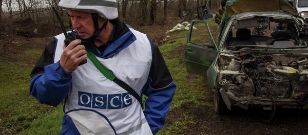 OSCE observers inspect a damaged car near Shyrokyne village, eastern Ukraine, Monday, March 30, 2015 - Sputnik Afrique