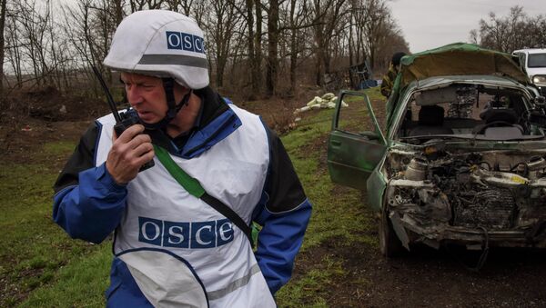 OSCE observers inspect a damaged car near Shyrokyne village, eastern Ukraine, Monday, March 30, 2015 - Sputnik Afrique