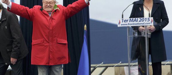 France's far-right National Front political party leader Marine Le Pen (R) watches as her father Jean-Marie Le Pen, party founder and honorary president, reacts on the podium at their traditional May Day tribute to Joan of Arc in Paris, France, May 1, 2015 - Sputnik Afrique