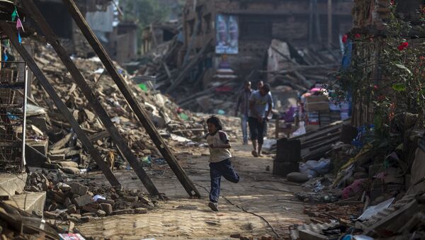 An earthquake survivor run past collapsed houses in Sankhu, on the outskirts of Kathmandu, Nepal, May 5, 2015 - Sputnik Afrique
