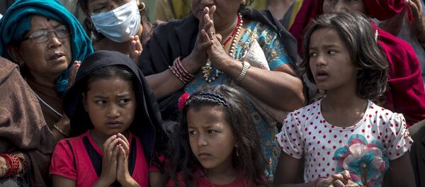 Local residents pray as they queue up for relief supplies distributed by international aid organisation after the April 25 earthquake in Bhaktapur, Nepal, May 10, 2015 - Sputnik Afrique