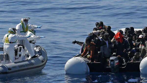 Italian Financial Police rescue unit approaches an inflatable dinghy crowded with migrants off the Libyan coast, in the Mediterranean Sea, Wednesday, April 22, 2015 - Sputnik Afrique