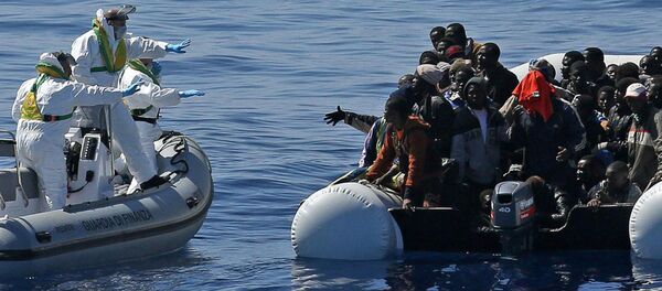 Italian Financial Police rescue unit approaches an inflatable dinghy crowded with migrants off the Libyan coast, in the Mediterranean Sea, Wednesday, April 22, 2015 - Sputnik Afrique
