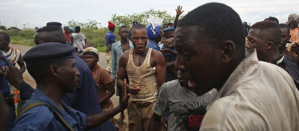 Protesters gesture near female police officer accused of shooting a protestor in Buterere neighbourhood of Bujumbura, Burundi - Sputnik Afrique