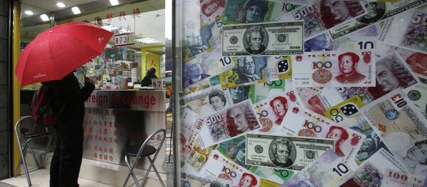 A man stands beside a collage of copies of Chinese RMB, U.S. dollar and other foreign bills at a money exchange store in Hong Kong Thursday, April 15, 2010 - Sputnik Afrique