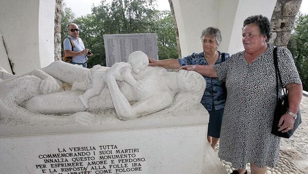 Lilia Pardini, right, and her sister Licia touch a sculpture depicting their mother and sister who were killed together with 560 people in 1944 by Nazi SS troops, at the 60th anniversary commemoration ceremony of the slaughter in Sant'Anna di Stazzema, Italy, Thursday, Aug. 12, 2004. - Sputnik Afrique