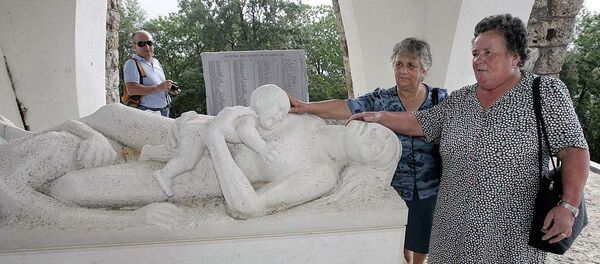 Lilia Pardini, right, and her sister Licia touch a sculpture depicting their mother and sister who were killed together with 560 people in 1944 by Nazi SS troops, at the 60th anniversary commemoration ceremony of the slaughter in Sant'Anna di Stazzema, Italy, Thursday, Aug. 12, 2004. - Sputnik Afrique