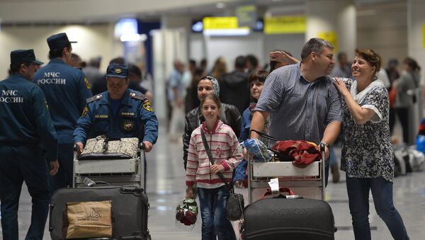 Сотрудник МЧС помогает донести багаж пассажирам, прилетевшим самолетом МЧС РФ из Сирии, в терминале аэропорта Домодедово. - Sputnik Afrique