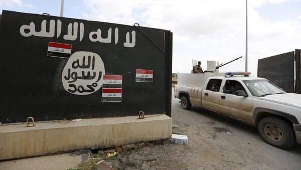 Iraqi security forces ride a vehicle past a wall painted with the black flag commonly used by Islamic State militants, near former Iraqi president Saddam Hussein's palace in Tikrit April 1, 2015 - Sputnik Afrique