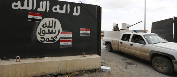 Iraqi security forces ride a vehicle past a wall painted with the black flag commonly used by Islamic State militants, near former Iraqi president Saddam Hussein's palace in Tikrit April 1, 2015 - Sputnik Afrique
