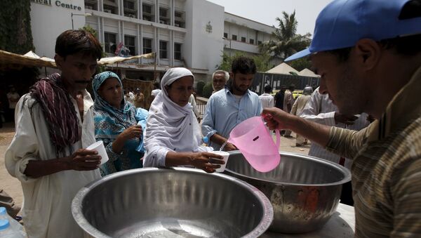 People receive drinking water from a volunteer at a stall, set up outside Jinnah Postgraduate Medical Centre (JPMC) during intense hot weather in Karachi, Pakistan, June 23, 2015. - Sputnik Afrique
