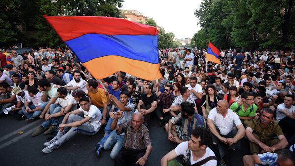Demonstrators wave their national flags as they sit during a protest against the increase of electricity prices in Yerevan, the capital of Armenia, on June 22, 2015. - Sputnik Afrique