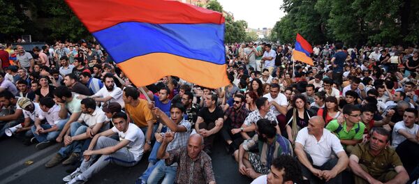Demonstrators wave their national flags as they sit during a protest against the increase of electricity prices in Yerevan, the capital of Armenia, on June 22, 2015. - Sputnik Afrique