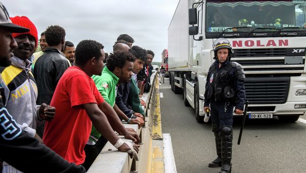 A French riot police officer (CRS) stands holdings his baton as illegal migrants wait to hide in lorries heading for England, in the French northern harbour of Calais, on June 17, 2015 - Sputnik Afrique