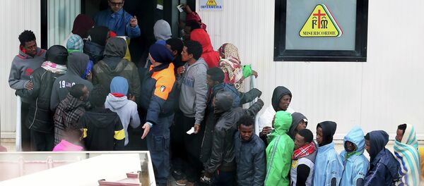Migrants stand in front of the infirmary at the immigration centre on the southern Italian island of Lampedusa - Sputnik Afrique