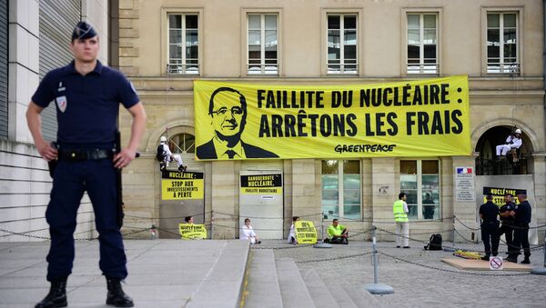 Police officers stand in front of the French Ministry for the Economy and Finance where Greenpeace activists gather and hung a large banner bearing a portrait of French President Francois Hollande and reading 'Bankruptcy of the nuclear, stop the costs' during an anti-nuclear protest, on July 1, 2015. - Sputnik Afrique