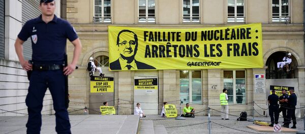Police officers stand in front of the French Ministry for the Economy and Finance where Greenpeace activists gather and hung a large banner bearing a portrait of French President Francois Hollande and reading 'Bankruptcy of the nuclear, stop the costs' during an anti-nuclear protest, on July 1, 2015. - Sputnik Afrique