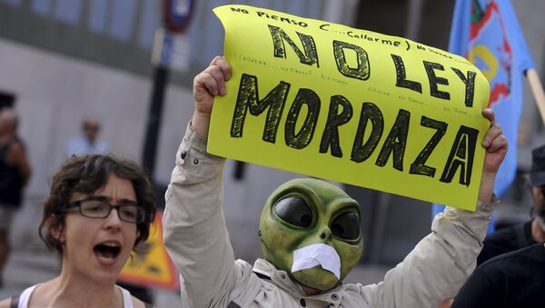A man wearing a mask with a tape over the mouth holds up a sign during a protest against the Spanish government's new security law in Gijon, northern Spain, June 30, 2015 - Sputnik Afrique