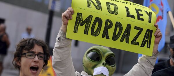A man wearing a mask with a tape over the mouth holds up a sign during a protest against the Spanish government's new security law in Gijon, northern Spain, June 30, 2015 - Sputnik Afrique