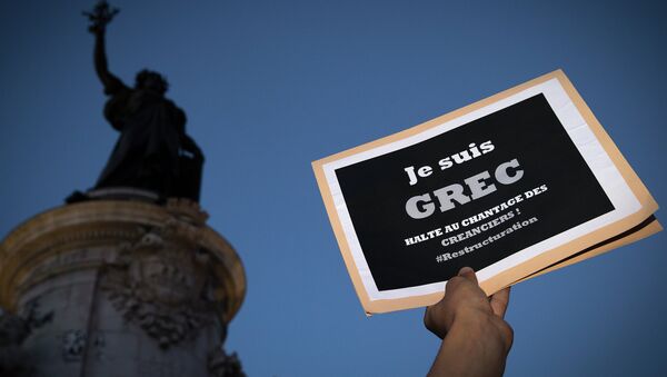 A person holds a banner reading  I am a Greek, stop at blackmail creditors during a rally in Paris on July 5, 2015 - Sputnik Afrique