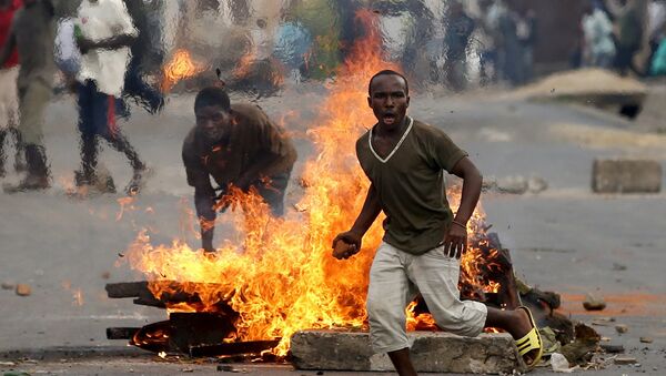 A protester runs in front of a burning barricade during a protest against Burundi President Pierre Nkurunziza and his bid for a third term in Bujumbura, Burundi, May 21, 2015 - Sputnik Afrique