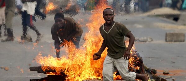 A protester runs in front of a burning barricade during a protest against Burundi President Pierre Nkurunziza and his bid for a third term in Bujumbura, Burundi, May 21, 2015 - Sputnik Afrique