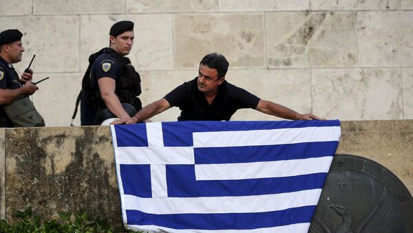 An anti-EU protester unfurls a Greek national flag next to riot police on the steps in front of the parliament building during a demonstration of about five hundred people in Athens, Greece July 13, 2015. - Sputnik Afrique