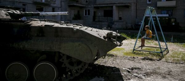 A boy sits on a swing near a building, which was damaged during fighting between Kiev and Donbass forces, as an armoured personnel carrier (APC) of the Ukrainian armed forces is seen nearby in Avdeyevka near Donetsk. June 7, 2015. A boy sits on a swing near a building, which was damaged during fighting between Kiev and Donbass forces, as an armoured personnel carrier (APC) of the Ukrainian armed forces is seen nearby in Avdeyevka near Donetsk. June 7, 2015. - Sputnik Afrique