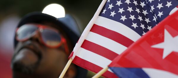 A man with small U.S. and Cuba flags stands on the sidewalk in the hours before officials raise the flag at the Cuban Embassy in Washington July 20, 2015. - Sputnik Afrique