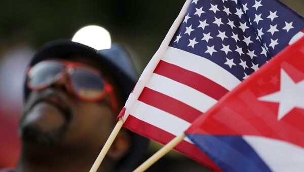A man with small U.S. and Cuba flags stands on the sidewalk in the hours before officials raise the flag at the Cuban Embassy in Washington July 20, 2015. - Sputnik Afrique