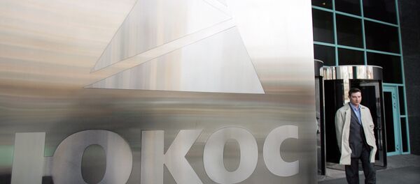 A man passes by a Yukos logo at the headquarters of the oil company in Moscow after the latest auction for the sale of package of assets the stricken giant, 04 April 2007 - Sputnik Afrique
