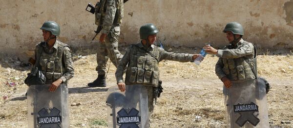 A Turkish soldier shares a bottle of water with his comrade as they stand guard near the Mursitpinar border gate in Suruc, bordering with Syrian town of Kobani, Sanliurfa province, Turkey, June 27, 2015. - Sputnik Afrique