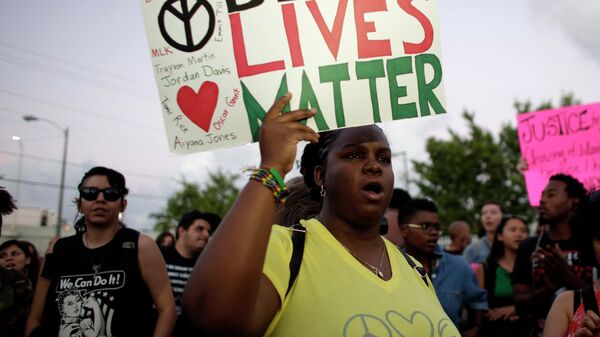 Desiree Griffiths, 31, of Miami, holds up a sign saying Black Lives Matter, with the names of Michael Brown and Eric Garner, two black men recently killed by police, during a protest - Sputnik Afrique