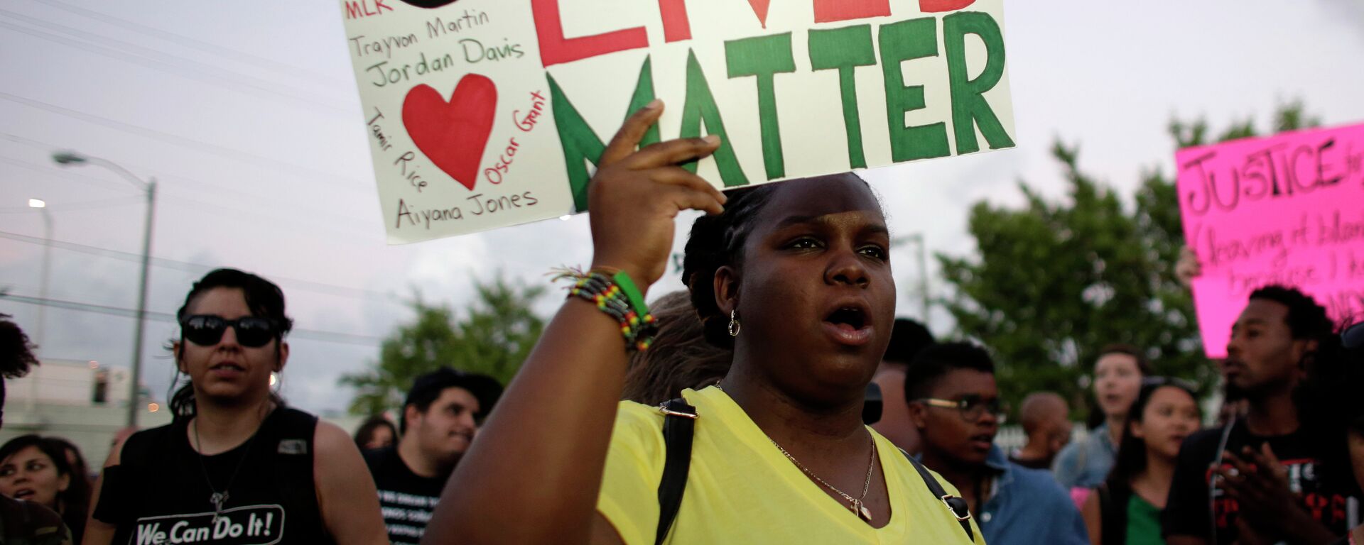 Une habitante de Miami, tient une pancarte Black Lives Matter, avec les nomes de Michael Brown et Eric Garner, deux hommes noirs tués par la police   - Sputnik Afrique, 1920, 04.03.2021