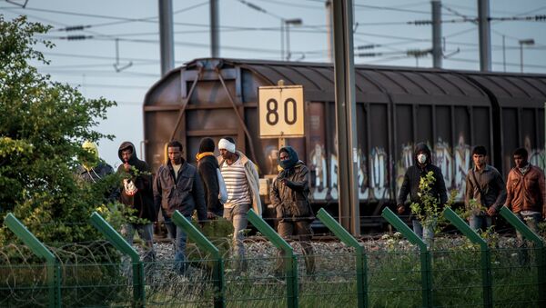 Migrants who successfully crossed the Eurotunnel terminal walk on the side of the railroad as they try to reach a shuttle to Great Britain, on July 28, 2015 in Frethun, northern France - Sputnik Afrique