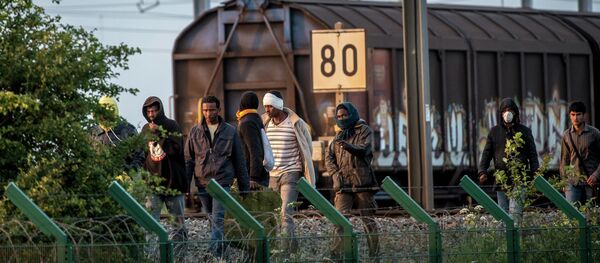 Migrants who successfully crossed the Eurotunnel terminal walk on the side of the railroad as they try to reach a shuttle to Great Britain, on July 28, 2015 in Frethun, northern France - Sputnik Afrique