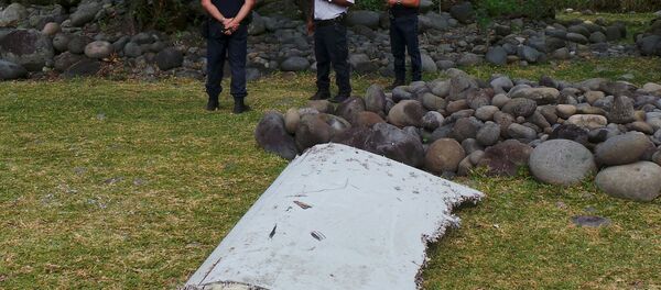 French gendarmes and police stand near a large piece of plane debris which was found on the beach in Saint-Andre, on the French Indian Ocean island of La Reunion, July 29, 2015. - Sputnik Afrique