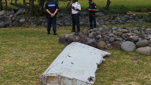 French gendarmes and police stand near a large piece of plane debris which was found on the beach in Saint-Andre, on the French Indian Ocean island of La Reunion, July 29, 2015. - Sputnik Afrique