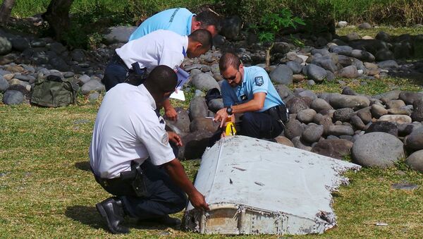 French gendarmes and police inspect a large piece of plane debris which was found on the beach in Saint-Andre, on the French Indian Ocean island of La Reunion, July 29, 2015 - Sputnik Afrique