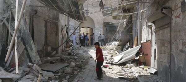 A boy walks past the damage after a Syrian army fighter jet crashed into a busy marketplace in the rebel-held northwestern town of Ariha August 3, 2015 - Sputnik Afrique