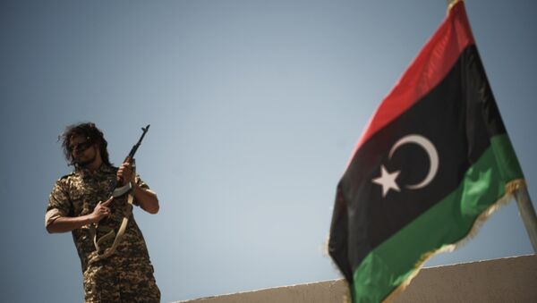 Un membre des forces de sécurité libyennes se tient sur un toit alors que le ministre libyen de la justice par intérim, Ali Hamiada, visite la nouvelle prison d'Al-Hadba et le tribunal spécial le 26 mai 2012 à Tripoli. La prison, qui peut accueillir 100 prisonniers politiques de haut rang, accueillera les procès des personnalités pro-mamer Kadhafi - Sputnik Afrique