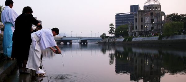 Shinto priests pray at the Motoyasu River opposite the Atomic Bomb Dome at sunrise in Hiroshima, western Japan, August 6, 2015. - Sputnik Afrique