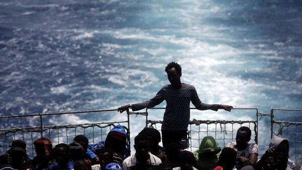 Migrants sit on the deck of the Belgian Navy vessel Godetia after they were saved at sea during a search and rescue mission in the Mediterranean Sea off the Libyan coasts, Wednesday, June 24, 2015. - Sputnik Afrique