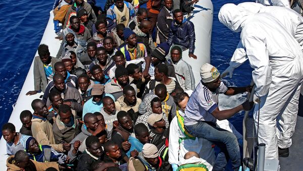 Migrants crowd and inflatable dinghy as rescue vassel  Denaro  of the Italian Coast Guard approaches them, off the Libyan coast, in the Mediterranean Sea, Wednesday, April 22, 2015 - Sputnik Afrique