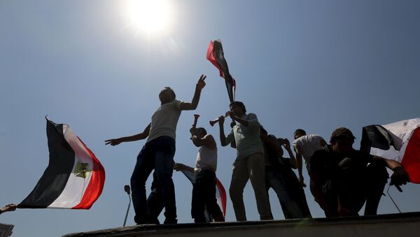 Les gens applaudissent en portant les drapeaux nationaux alors qu'ils se rassemblent sur la place Tahrir pour célébrer l'extension du canal de Suez, au Caire, en Égypte, le 6 août 2015. L'Égypte inaugurera jeudi en grande pompe le prolongement du canal de Suez, pièce maîtresse des plans du président Abdel Fattah al-Sisi pour revitaliser l'économie du pays après des années de troubles politiques préjudiciables.  - Sputnik Afrique